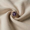 Goldfarbener Ring mit lila Mittelstein und dreifacher Ringschiene