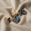 Blaue kristallene Halskette mit goldenen Ohrringen an einer silbernen Kette